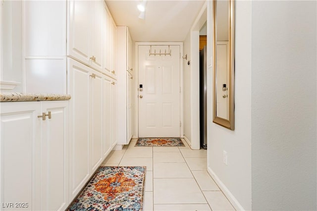 doorway featuring light tile patterned flooring and baseboards