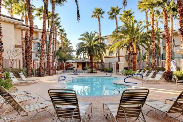 community pool with a patio area and fence