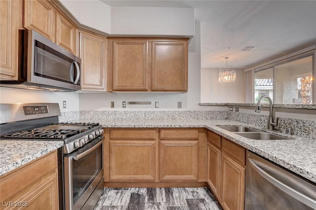 kitchen featuring light stone countertops, a notable chandelier, stainless steel appliances, and a sink