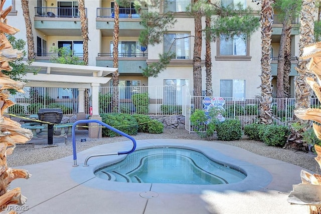 view of swimming pool with fence and a hot tub