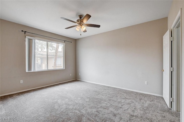 carpeted spare room with a ceiling fan and baseboards