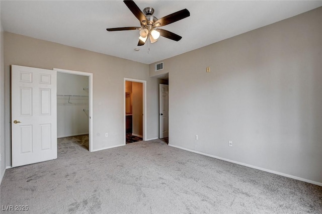 unfurnished bedroom featuring a walk in closet, a closet, visible vents, carpet flooring, and baseboards