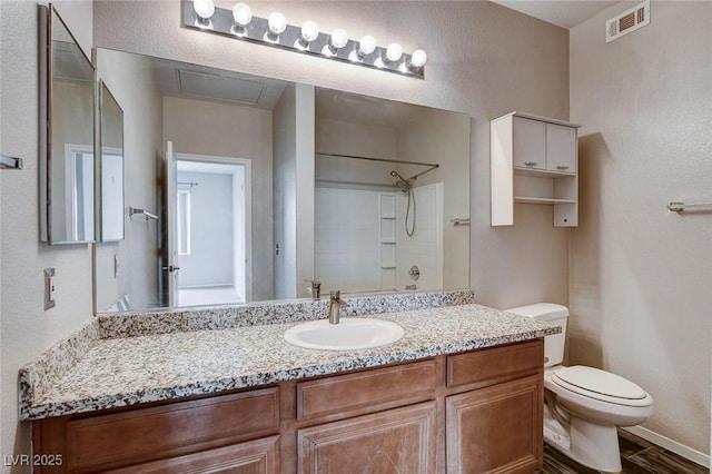 bathroom featuring visible vents, a textured wall, toilet, vanity, and walk in shower