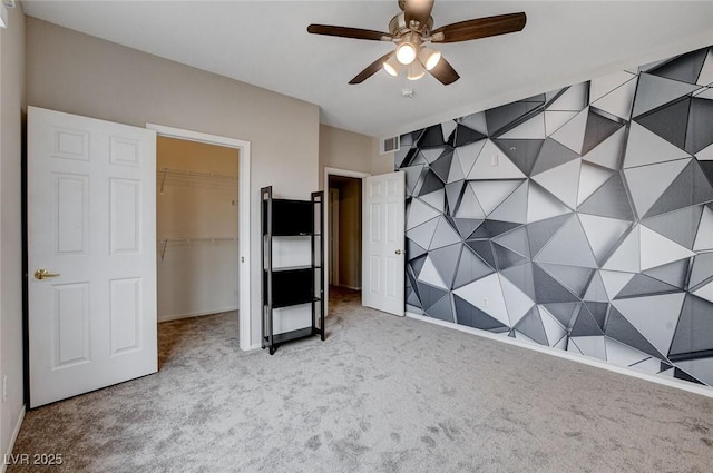 unfurnished bedroom with visible vents, a ceiling fan, a walk in closet, carpet flooring, and a closet