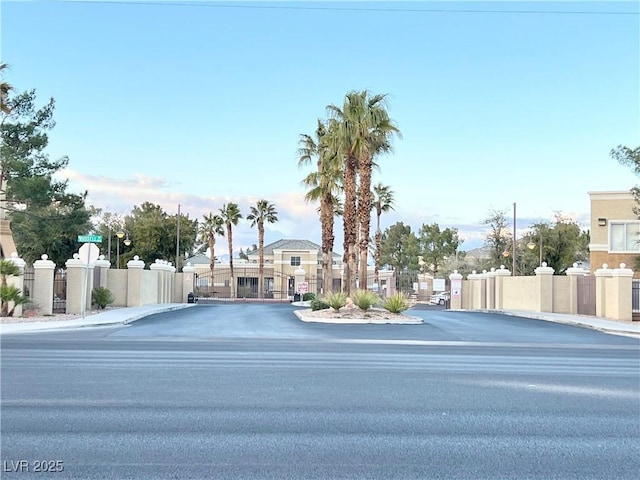 view of street with a gate, curbs, and sidewalks