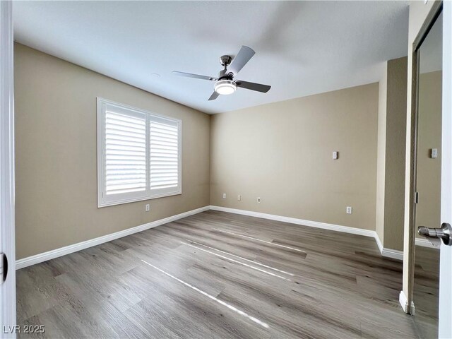 interior space with ceiling fan, wood finished floors, and baseboards