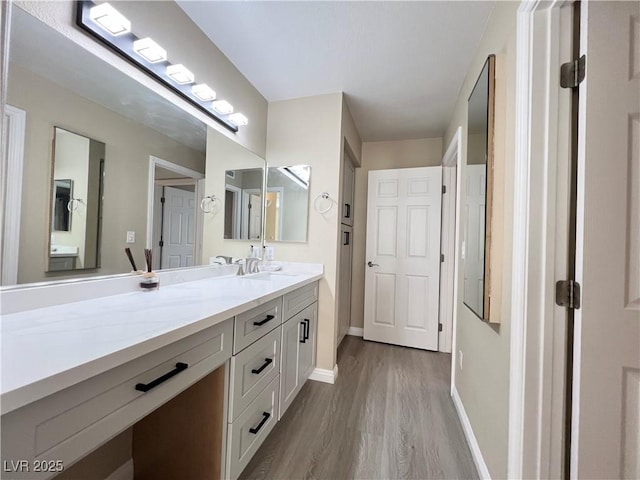 bathroom with wood finished floors, vanity, and baseboards