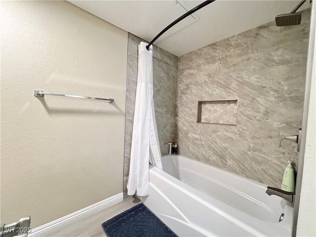 full bath with shower / bath combo, baseboards, wood finished floors, and a textured wall