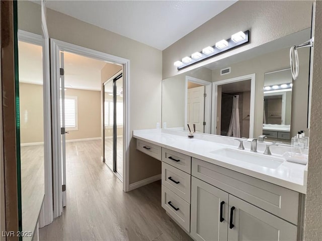 bathroom with baseboards, visible vents, wood finished floors, and vanity