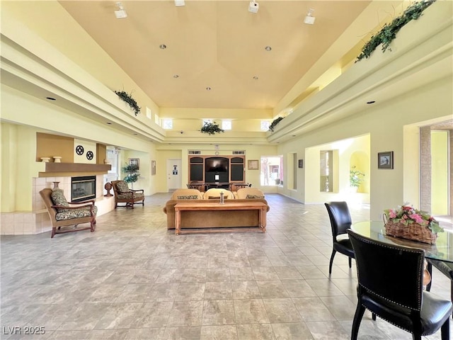 living area featuring a glass covered fireplace, a high ceiling, and light tile patterned floors