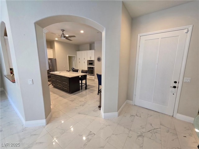 foyer with baseboards, arched walkways, and marble finish floor