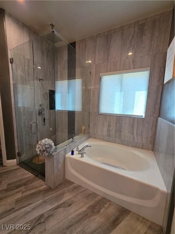 bathroom with a shower stall, a bath, and wood finished floors