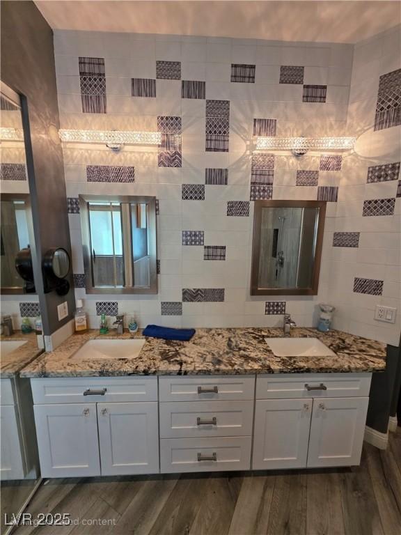 bathroom featuring double vanity, wood finished floors, tasteful backsplash, and a sink