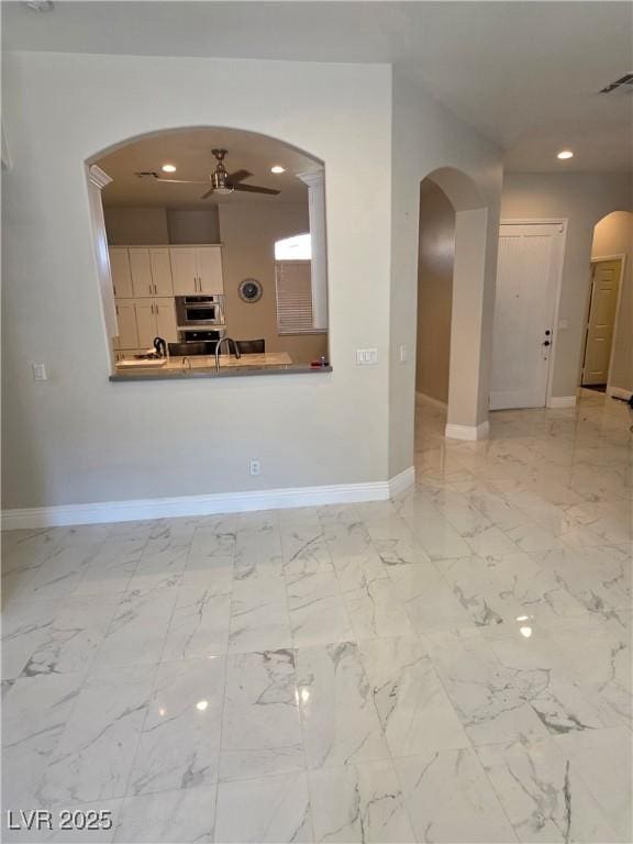 unfurnished living room featuring visible vents, baseboards, arched walkways, and marble finish floor