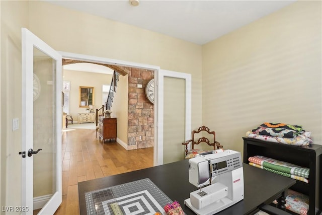 office area with arched walkways and wood finished floors