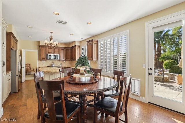 dining area with baseboards, visible vents, light wood-type flooring, a chandelier, and recessed lighting