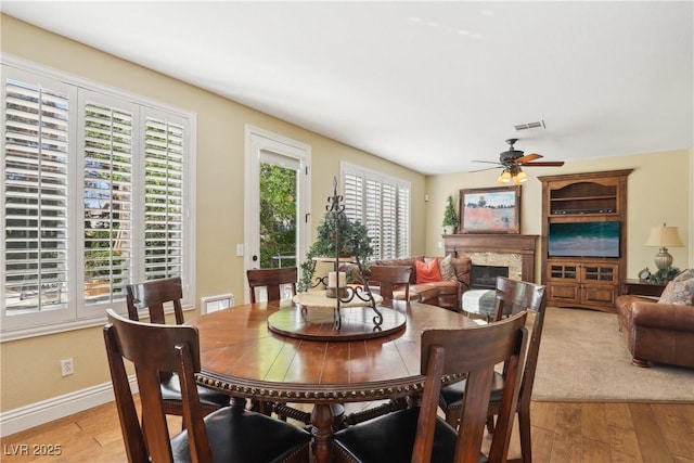 dining space with light wood-type flooring, plenty of natural light, and a fireplace