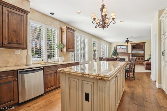 kitchen featuring plenty of natural light, light wood-type flooring, a sink, and stainless steel dishwasher