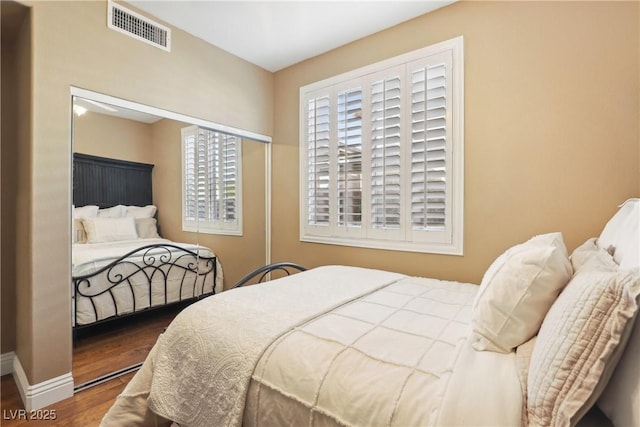 bedroom featuring wood finished floors, visible vents, and baseboards