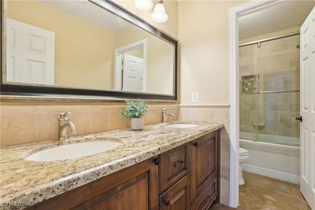 bathroom with toilet, double vanity, tile walls, and a sink