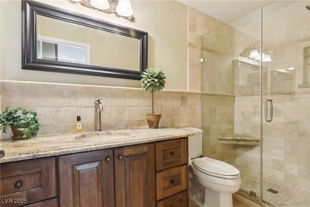 full bath with toilet, a stall shower, vanity, and tile walls