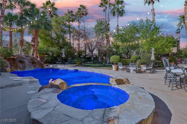 pool with a patio area and an in ground hot tub