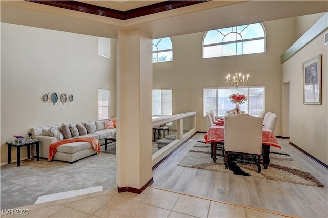 carpeted dining space with tile patterned flooring, baseboards, a high ceiling, and an inviting chandelier