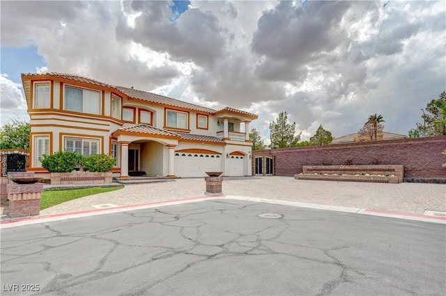 mediterranean / spanish home featuring a garage, driveway, a tiled roof, and stucco siding