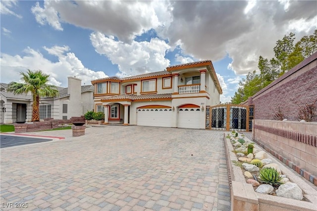 mediterranean / spanish-style home featuring an attached garage, fence, a tiled roof, decorative driveway, and stucco siding