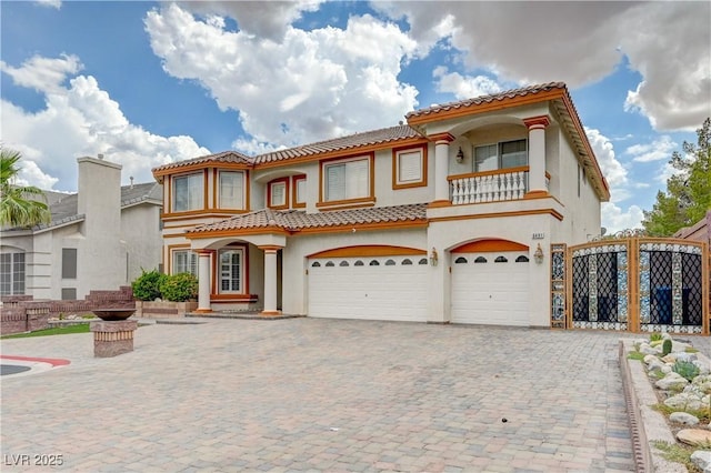 mediterranean / spanish house featuring a garage, decorative driveway, a balcony, and stucco siding