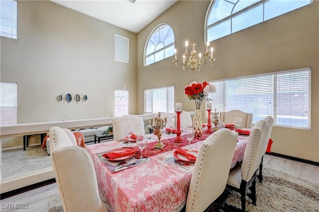 dining room with wood finished floors, baseboards, a high ceiling, and an inviting chandelier