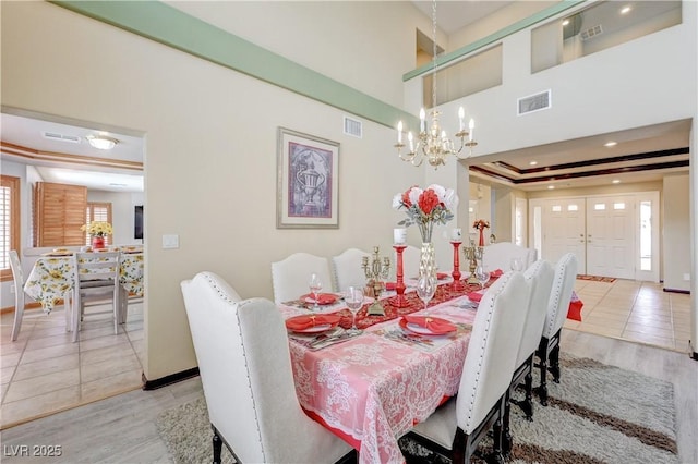 dining room featuring a raised ceiling, visible vents, and light tile patterned flooring