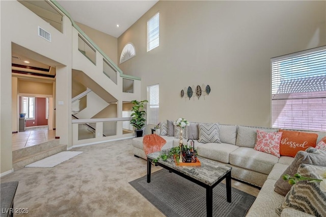 carpeted living room with a high ceiling, tile patterned flooring, and visible vents