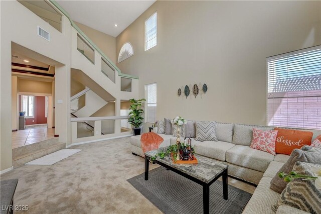 living room with a towering ceiling, carpet, visible vents, and tile patterned floors