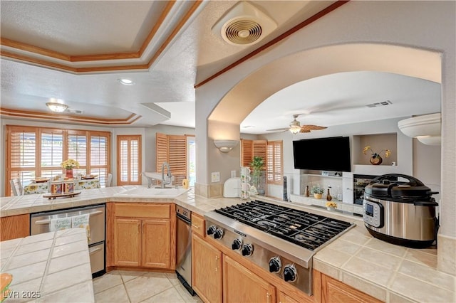 kitchen featuring a sink, visible vents, appliances with stainless steel finishes, tile counters, and a raised ceiling