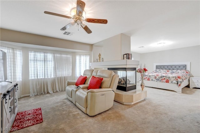 bedroom with ceiling fan, visible vents, a tiled fireplace, and light colored carpet