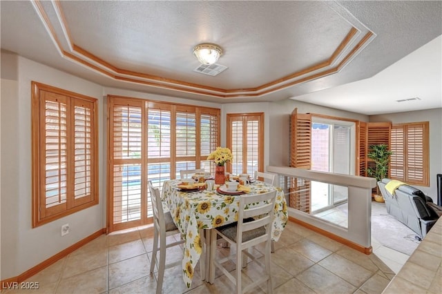 dining space with a textured ceiling, a raised ceiling, and baseboards