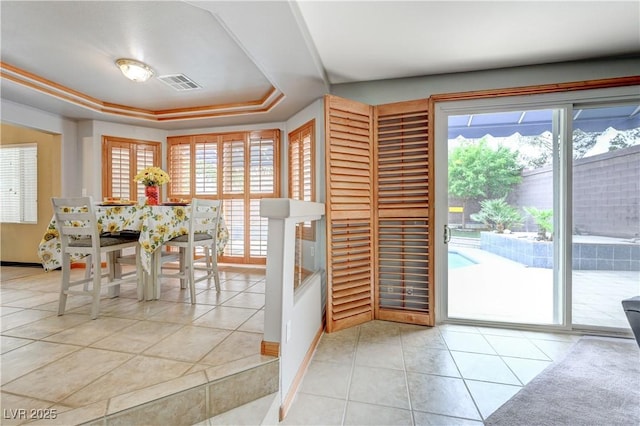 dining area with a wealth of natural light, a raised ceiling, visible vents, and light tile patterned floors