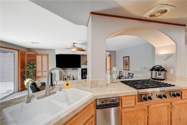 kitchen with visible vents, arched walkways, a ceiling fan, stainless steel gas cooktop, and a sink