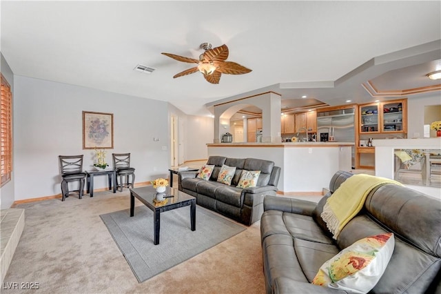 living room featuring light carpet, ceiling fan, visible vents, and baseboards