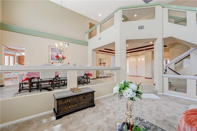 carpeted living room featuring a chandelier, recessed lighting, visible vents, and a high ceiling