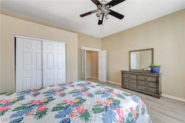 bedroom with light wood-type flooring, a ceiling fan, baseboards, and a closet