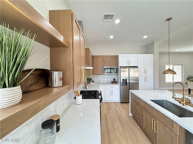 kitchen featuring light stone counters, visible vents, a sink, appliances with stainless steel finishes, and backsplash