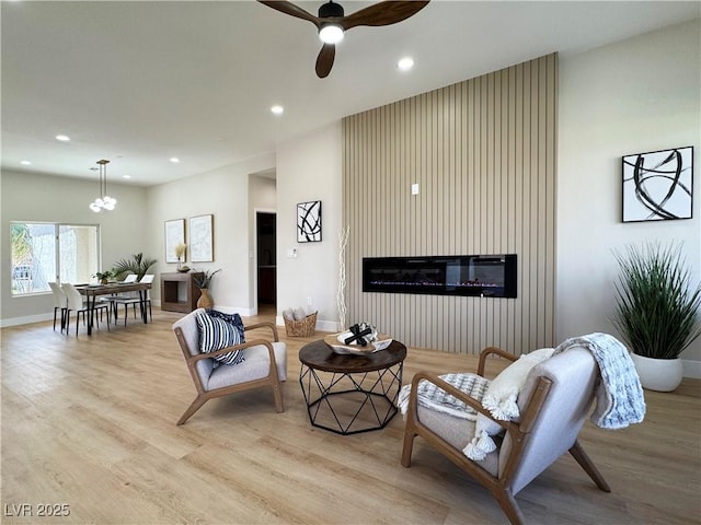 living area with recessed lighting, a large fireplace, and light wood-style floors