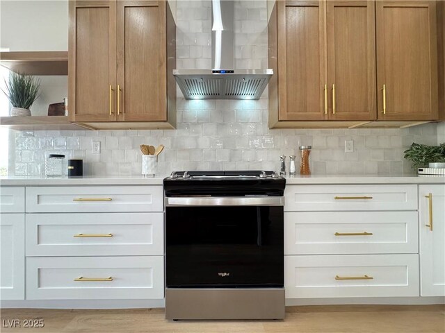 kitchen with tasteful backsplash, electric range, light countertops, and wall chimney range hood