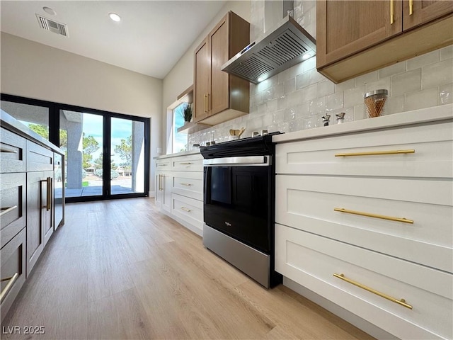 kitchen with visible vents, range with electric cooktop, light wood-style floors, wall chimney exhaust hood, and decorative backsplash