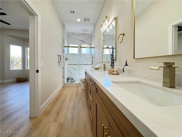 full bath with a wealth of natural light, a marble finish shower, toilet, and wood finished floors