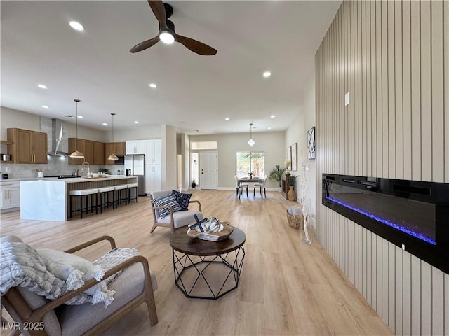 living room featuring recessed lighting, baseboards, light wood-style floors, and ceiling fan