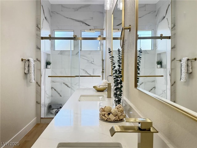 bathroom with a marble finish shower, baseboards, a wealth of natural light, and double vanity