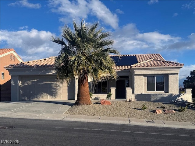 view of front of home featuring driveway, solar panels, an attached garage, stucco siding, and a tile roof